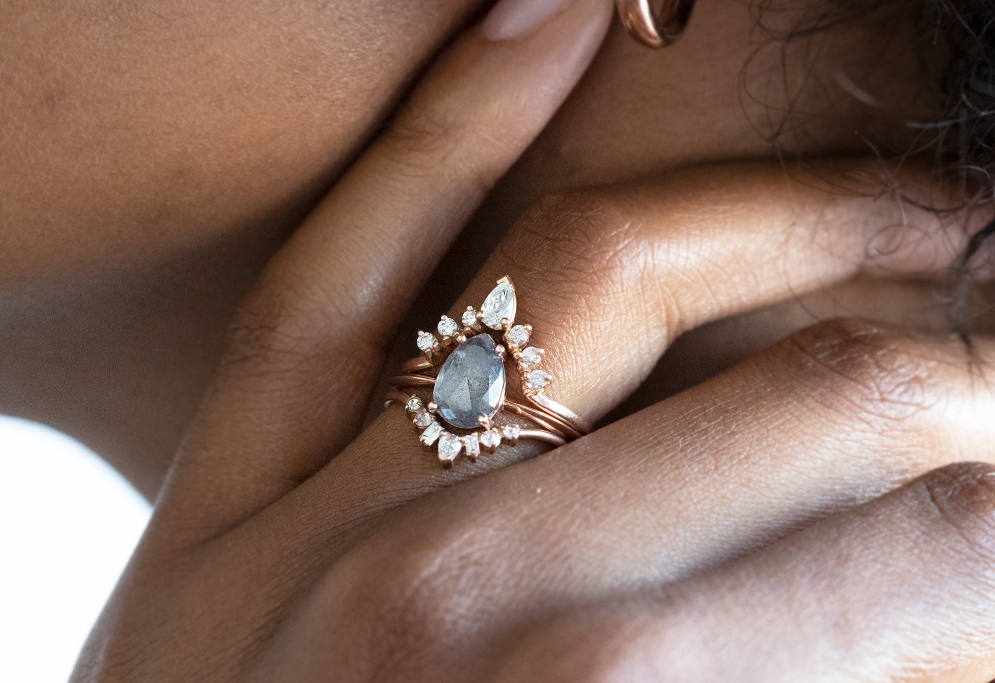 Model wearing salt and pepper pear diamond engagement ring with white diamond stacking bands