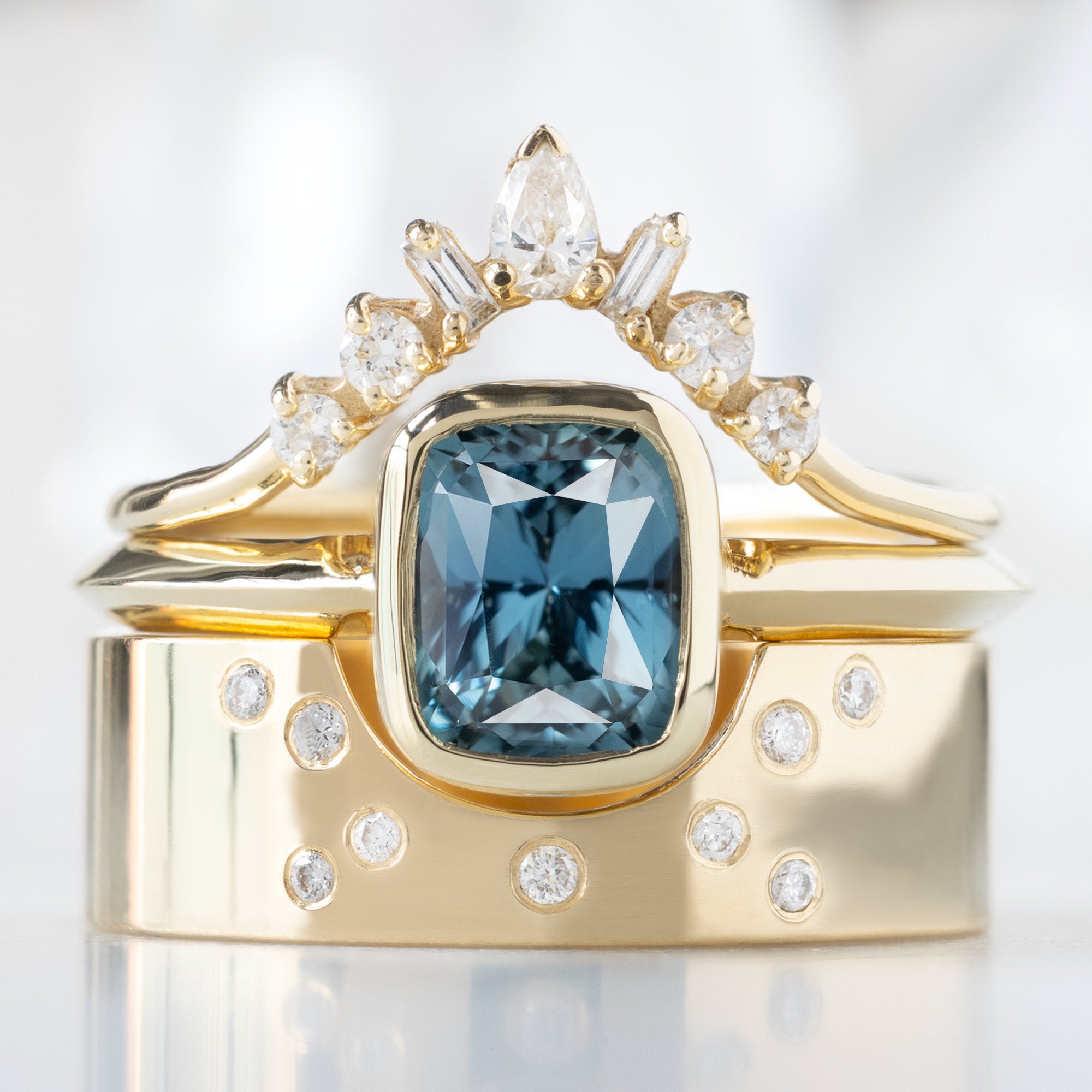 buy:geometric-white-diamond-sunburst-stacking-band-14k-or-18k-yellow-gold,the-hazel-ring-1-78ct-cushion-cut-blue-sapphire-in-14k-yellow-gold,constellation-cut-out-stacking-band-arc-cut-out-in-14k-yellow-gold